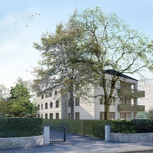 Mehrstöckiges Wohnhaus mit Balkonen, umgeben von Bäumen und Hecken, Einfahrt mit Tor und Straße im Vordergrund